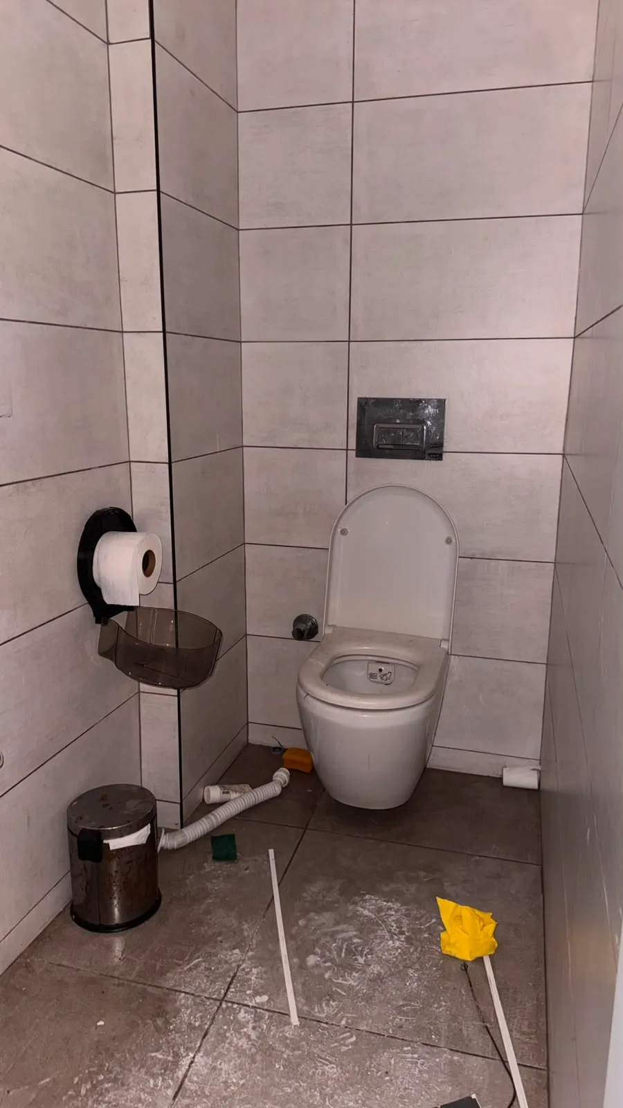 Açık gri duvar karoları ve koyu gri zemini bulunan ayrı tuvalet alanının genel görünümü.